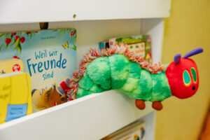 Bilderbuch und Kuschelraupe im Regal